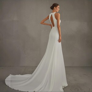 May include: A white wedding dress with a halter neckline and a flowing skirt. The dress features a keyhole back and a long train. The image is set against a neutral gray background. The Versailles logo is in the top left corner.