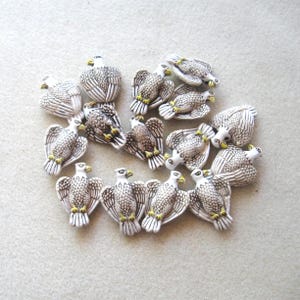 May include: A collection of small, white eagle figurines with detailed feather patterns. The eagles have brown and gray markings, yellow beaks and feet. These decorative figurines are ideal for crafting or collecting.
