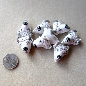 May include: Seven white ceramic buffalo head charms with black eyes and noses. The charms are about the size of a US quarter.