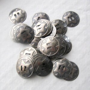 May include: A pile of silver-toned metal buttons with a star and the number "II" in the center. The buttons are oval shaped and have a textured surface.