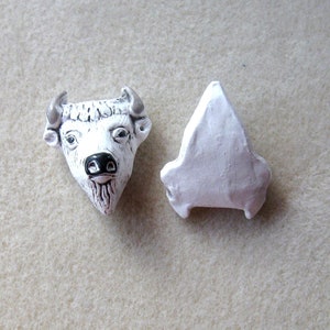 May include: White ceramic bull head with black nose and horns, and a separate white ceramic piece shaped like a triangle.