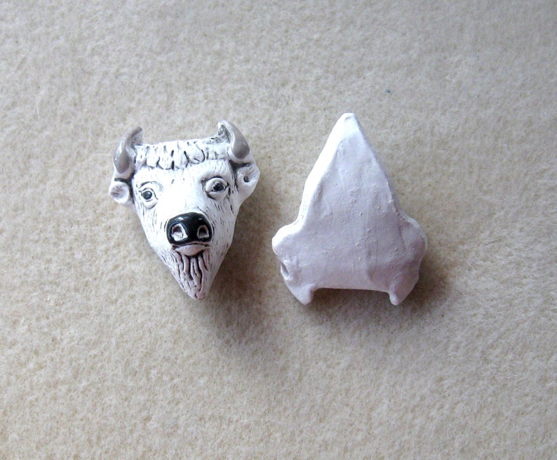May include: White ceramic bull head with black nose and horns, and a separate white ceramic piece shaped like a triangle.