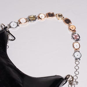 May include: A black handbag with a chain strap made of various wristwatches. The watches have different colored faces and bands, including silver, gold, and rose gold. The watches are attached to a chain that forms the strap.