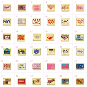 May include: A selection of gold-coloured charm pendants, each with a unique design and text such as "Sugar," "Barbie," and "I Love Strawberries." The charms have colourful enamel details and are displayed against a pink backdrop.