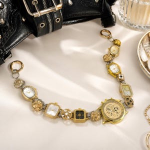 May include: A decorative chain constructed from various gold-toned watch faces and metallic circular links. The piece features a large central watch dial with an exposed gear mechanism, surrounded by smaller rectangular and oval watch faces.