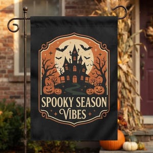 May include: A black rectangular garden flag featuring a central orange circular graphic with a silhouette of a haunted house, bare trees, bats, and pumpkins. The text "SPOOKY SEASON VIBES" is printed in a bold, decorative font below the illustration.