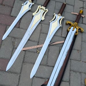 May include: Four swords with silver blades and ornate gold and silver hilts. The handles are wrapped in brown leather. One sword is in a brown leather sheath with a strap.
