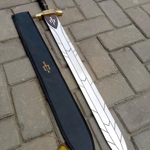 以下が含まれることがあります： 装飾的な刃のデザインと茶色の柄が付いた銀色の剣。黒い革の鞘の隣に置かれています。剣は金色の柄と刃にシンボルが付いています。鞘にも同じシンボルが付いています。