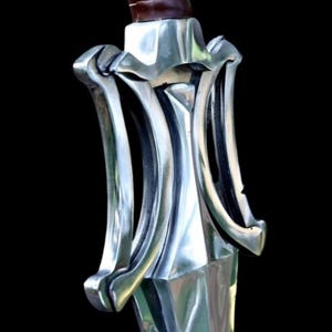 May include: Close-up of a silver sword hilt with a brown leather-wrapped handle. The hilt features a decorative, symmetrical design with curved, polished metal elements. The blade is not visible. The background is black.