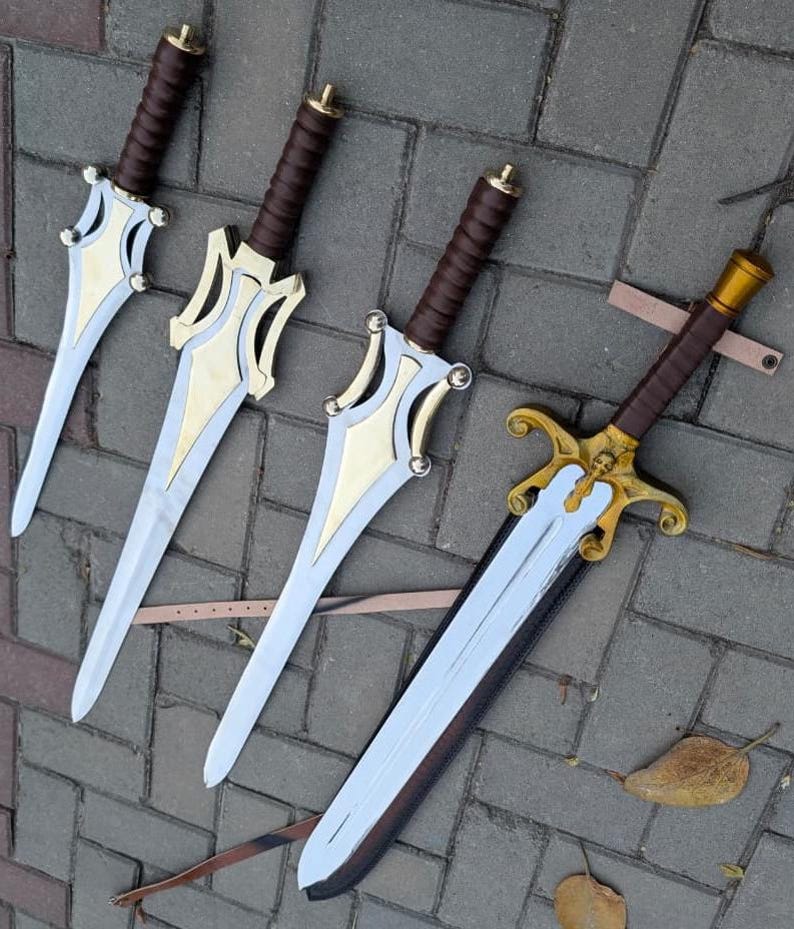 May include: Four fantasy swords with silver blades, gold accents, and brown wrapped handles. The swords are arranged on a gray brick surface. One sword has a skull design on the hilt and a leather sheath.