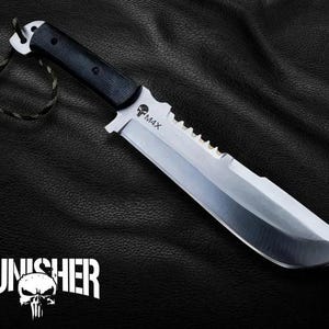 May include: A large, silver and black knife with a serrated edge and the text "M4X". The handle is black and the blade is silver. The text "THE PUNISHER" is displayed below the knife, along with a skull logo.