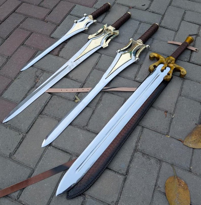May include: Four swords with polished steel blades and ornate gold-colored hilts. The handles are wrapped in brown leather. One sword is sheathed in a brown leather scabbard. The swords are arranged on a gray brick surface.