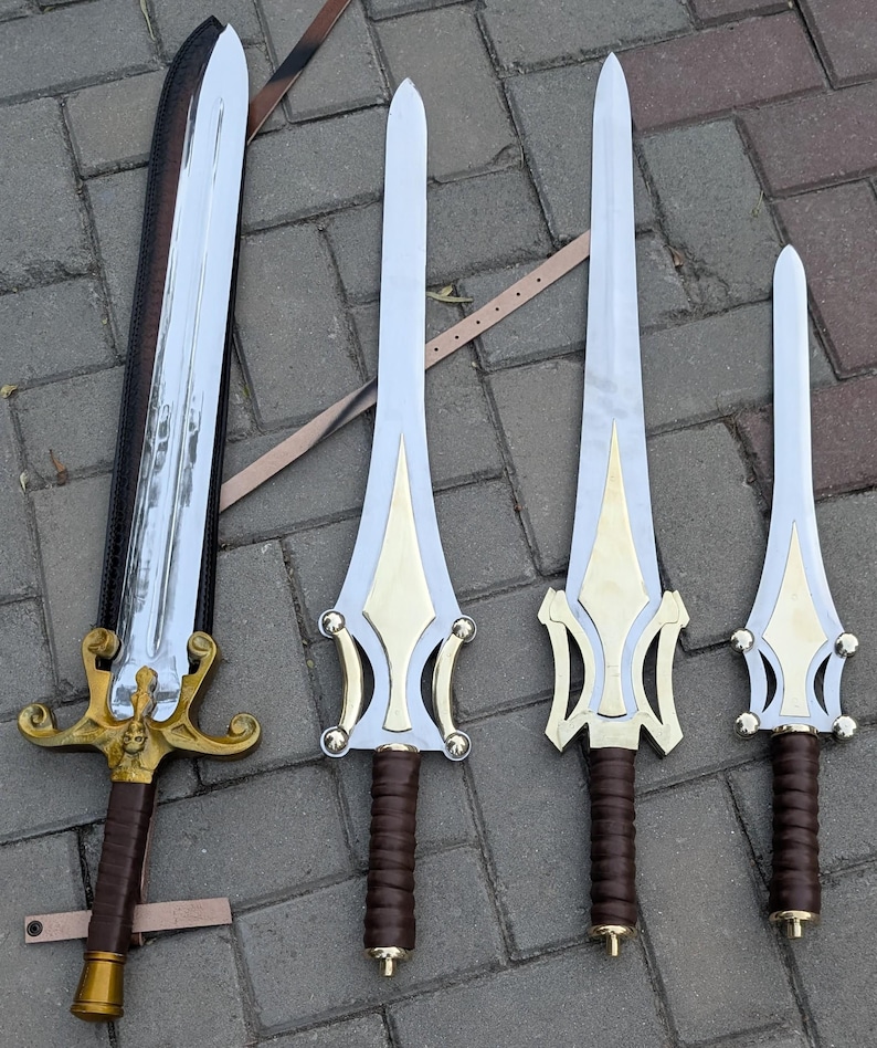 May include: Collection of four swords with silver blades and gold-colored hilts. The hilts have intricate designs and brown leather-wrapped handles. One sword is in a black sheath. The swords vary in size, with the largest measuring approximately 36 inches.
