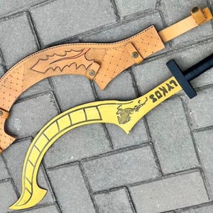 May include: A curved yellow sword with a black handle and the text LYKOS printed on the blade, accompanied by a tan leather sheath featuring embossed leaf patterns and a grid design, secured with small metallic rivets and a strap.
