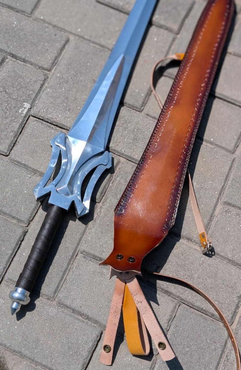 Pu&ograve; includere: Una spada color argento con un'elsa stilizzata e un'impugnatura nera &egrave; appoggiata accanto a un fodero in pelle marrone. Il fodero presenta cuciture decorative e un cinturino con fibbia. La spada &egrave; un oggetto a tema fantasy.