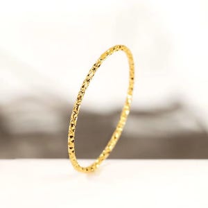 May include: A thin gold ring with a textured surface.