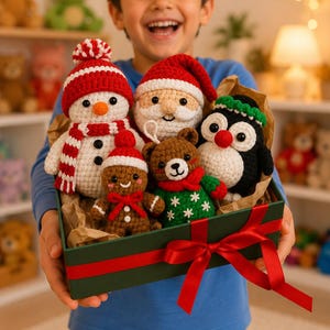 Könnte beinhalten: Eine Sammlung von fünf kleinen gehäkelten Weihnachtsfiguren, darunter ein Schneemann, der Weihnachtsmann, ein Lebkuchenmännchen, ein Teddybär und ein Pinguin, in einer dunkelgrünen Geschenkbox mit einer roten Schleife.