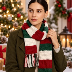 May include: A chunky knit scarf featuring horizontal stripes in dark green, deep red, and off-white. The scarf has a thick, textured yarn construction and is finished with long, multi-colored fringe tassels at the ends, creating a classic winter accessory.