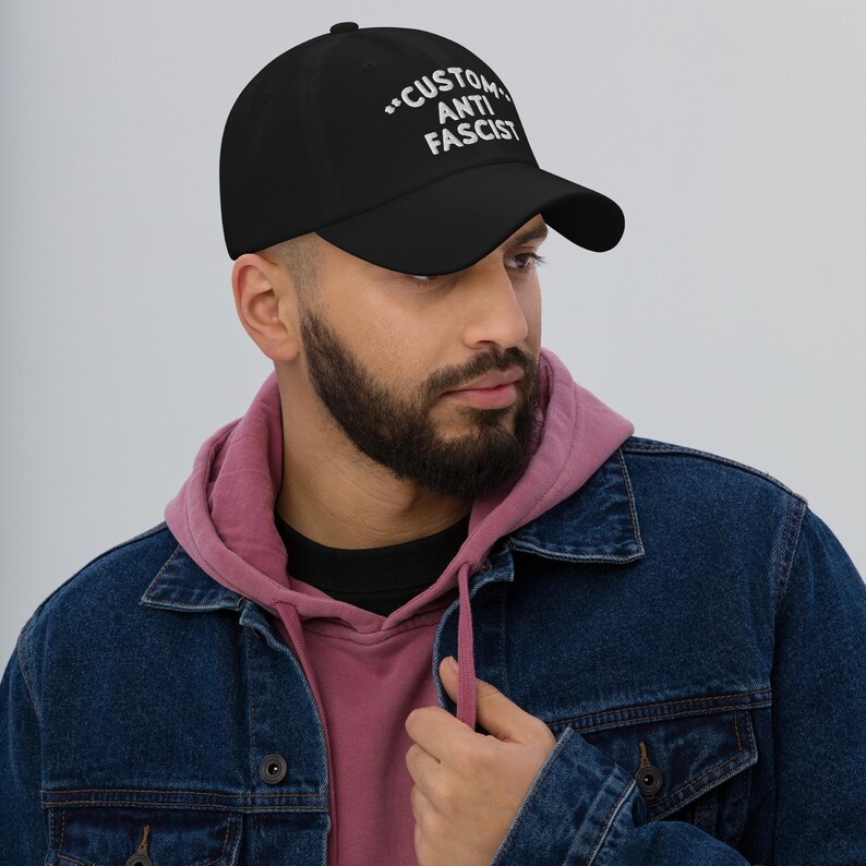 Model wearing the black “Custom Anti Fascist” dad hat with white embroidery and casual streetwear.