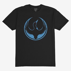 May include: Black t-shirt featuring a light blue bird design within a circle. The bird has outstretched wings and a red eye. The word "STRANDS" is printed on the collar. A casual tee for everyday wear.