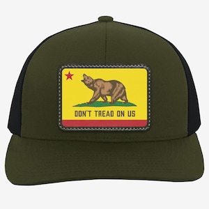 May include: Olive green trucker hat with a black mesh back. The front features a patch with the California state flag: a brown bear on a yellow background, a red stripe, and the text "DON'T TREAD ON US."