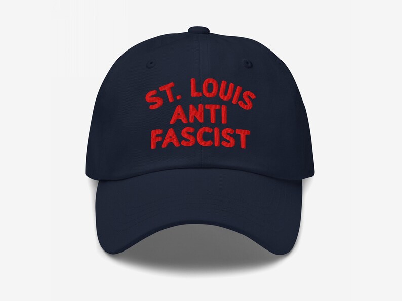 Navy blue dad hat with “St. Louis Anti Fascist” in bold red embroidery, showing contrast customization.
