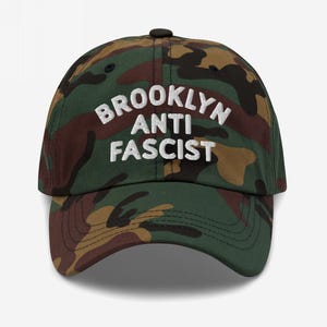 Camo dad hat with “Brooklyn Anti Fascist” embroidered in white, showcasing a custom city option.