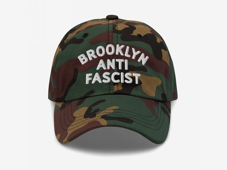 Camo dad hat with “Brooklyn Anti Fascist” embroidered in white, showcasing a custom city option.