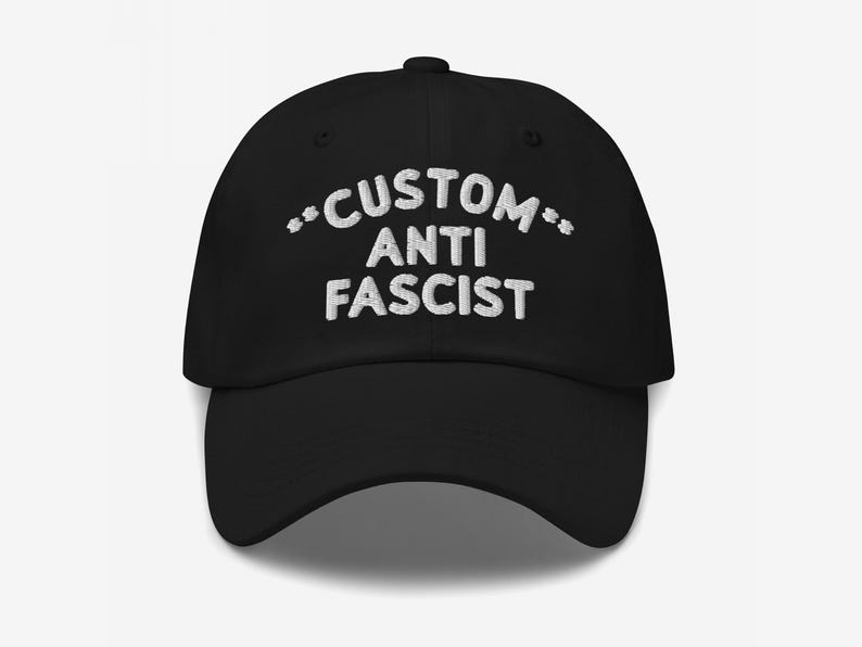 Front view of black unstructured dad hat with “Custom Anti Fascist” embroidered in white thread.