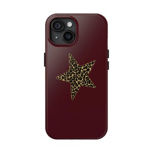 Pode incluir: Uma capa de telefone bordô com um design de estrela com estampa de leopardo. A capa tem um acabamento brilhante e um recorte para a câmera. A estrela é um padrão bege e preto. A capa é projetada para um smartphone.