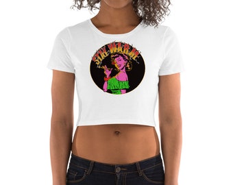 Könnte beinhalten: Weißes, bauchfreies T-Shirt mit einem schwarzen Kreis-Motiv, das eine Frau mit rosa Haut und grüner Kleidung zeigt. Der Text "STAY WARM" ist in roten und gelben Buchstaben um den Kreis herum angeordnet.