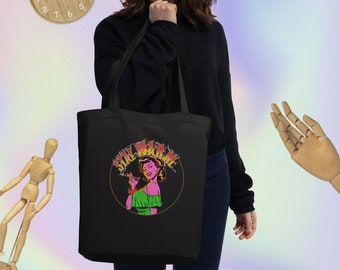 Könnte beinhalten: Schwarze Einkaufstasche mit einem Grafikdruck einer Frau, die eine Zigarette hält, und dem Text "Stay Warm" in einem Kreis mit Flammen drumherum.