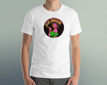 Könnte beinhalten: Weißes T-Shirt mit einem schwarzen Kreis-Motiv, das eine Frau mit rosa Haut und grünen Haaren zeigt. Der Text "Stay Weird" ist in gelben, orangefarbenen und roten Buchstaben um den Kreis herum geschrieben.