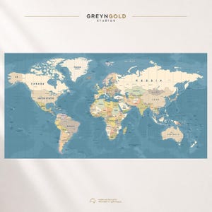 May include: A world map wall art print featuring a muted color palette with beige landmasses and a deep blue ocean. The text GREYNGOLD STUDIOS appears at the top center, and the text PREMIUM QUALITY PRINTED IN AUSTRALIA is at the bottom center.