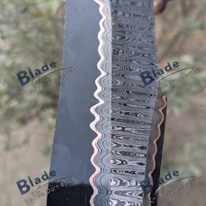 Pode incluir: Close-up de uma l&acirc;mina de faca com uma superf&iacute;cie escura e texturizada e uma borda ondulada e padronizada. A borda apresenta um detalhe em cor de cobre. A l&acirc;mina tem um padr&atilde;o em camadas e rodopiante em tons de cinza e preto. O texto "Blade Knife Domestic" &eacute; vis&iacute;vel.