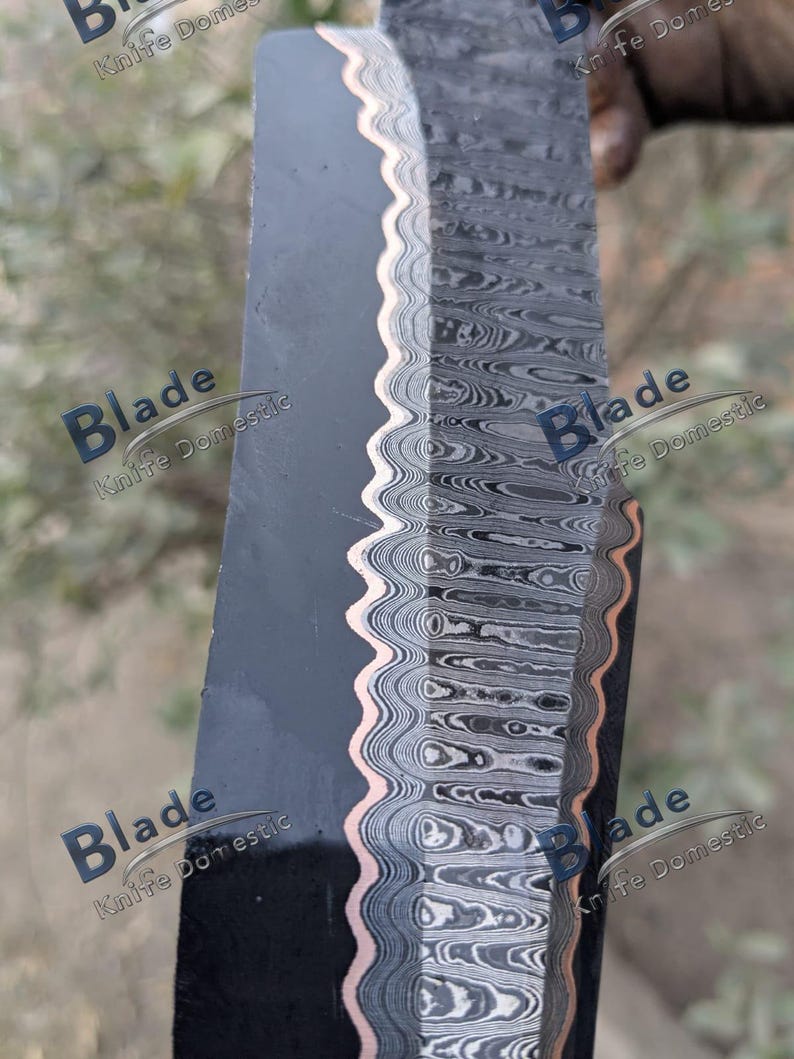 Pode incluir: Close-up de uma l&acirc;mina de faca com uma superf&iacute;cie escura e texturizada e uma borda ondulada e padronizada. A borda apresenta um detalhe em cor de cobre. A l&acirc;mina tem um padr&atilde;o em camadas e rodopiante em tons de cinza e preto. O texto "Blade Knife Domestic" &eacute; vis&iacute;vel.
