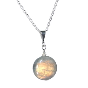May include: A silver chain necklace with a round, iridescent labradorite pendant.