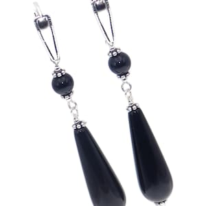 May include: A pair of dangle earrings with black onyx teardrop-shaped stones and round beads. The earrings have silver-toned metal clasps.