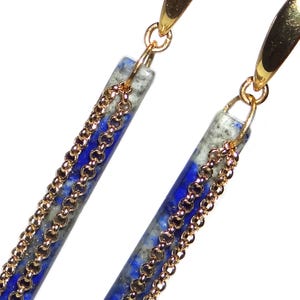 May include: A pair of long, gold dangle earrings with blue and white stone accents and gold chains.