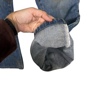 K&ouml;nnte beinhalten: Nahaufnahme einer hellblauen Jeans. Der Saum der Jeans ist hochgekrempelt und zeigt den Innenstoff und die N&auml;hte. Die Jeans ist abgenutzt und hat ein verwaschenes Aussehen.