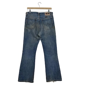 K&ouml;nnte beinhalten: Hellblaue Jeans mit klassischem F&uuml;nf-Taschen-Design, mit einem Used-Look und einem Lederaufn&auml;her auf der R&uuml;ckseite. Die Jeans h&auml;ngen an einem Holzkleiderb&uuml;gel.