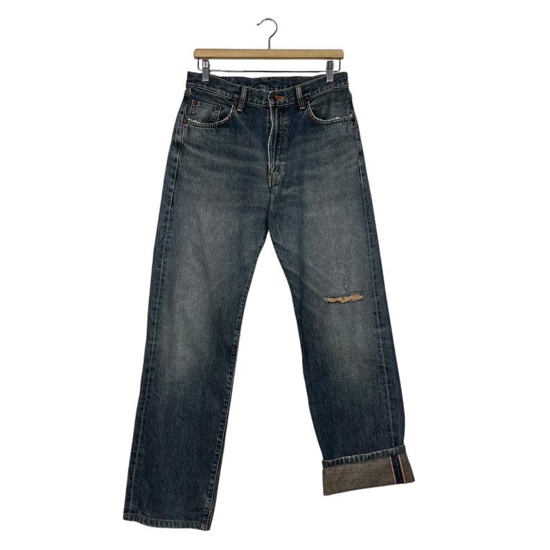 May include: A pair of blue denim jeans with a distressed knee and cuffed hems.