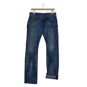 K&ouml;nnte beinhalten: Blaue Jeans aus Denim mit verwaschener Optik, klassischem F&uuml;nf-Taschen-Design und geradem Bein. Die Jeans h&auml;ngen an einem Holzkleiderb&uuml;gel. Die Manschetten sind hochgekrempelt und es gibt dezente Used-Details.