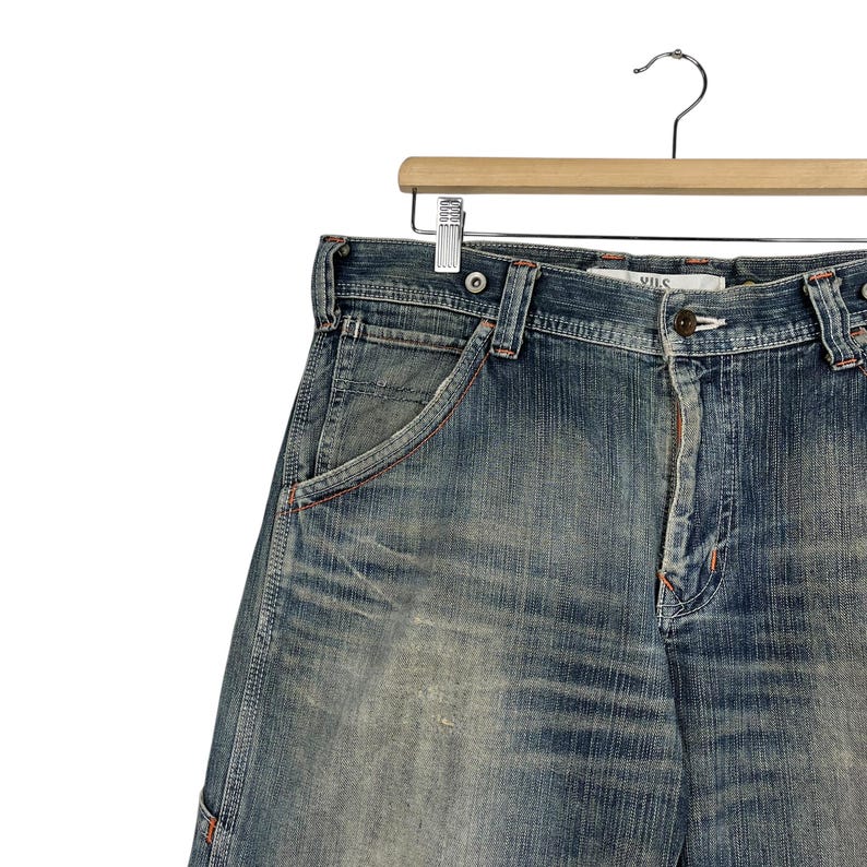 May include: Faded blue denim shorts with a classic five-pocket design. The shorts have a button closure, belt loops, and a small coin pocket. The denim has a worn, distressed appearance.