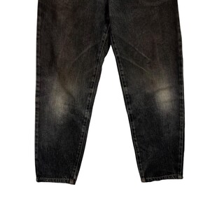 Puede incluir: Un par de vaqueros de mezclilla gris oscuro. Los vaqueros tienen un aspecto descolorido con parches m&aacute;s claros en los muslos y las rodillas. La mezclilla es de peso medio, con costuras visibles y un dise&ntilde;o cl&aacute;sico de cinco bolsillos.