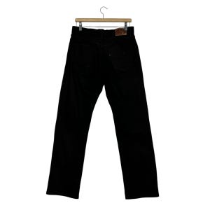 May include: Black corduroy pants hanging on a wooden hanger. The pants have a classic five-pocket design and a leather patch on the back. The pants are a solid black color.