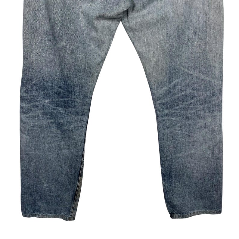 May include: Light blue denim jeans with a faded wash and subtle distressing. The jeans have a classic five-pocket design and a straight leg fit. The denim has a worn appearance.