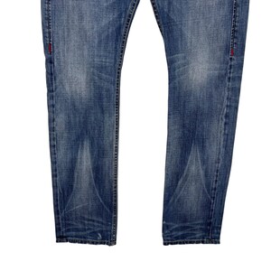 K&ouml;nnte beinhalten: Verblasste blaue Jeans aus Denim mit klassischem F&uuml;nf-Taschen-Design. Die Jeans haben einen geraden Beinverlauf und weisen subtile Abnutzungsmuster auf. Rote N&auml;hte akzentuieren die N&auml;hte.