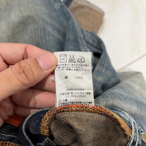 May include: Close-up of denim fabric with a label showing washing instructions and fabric composition. The label indicates a 40-degree wash, and the material is 100% cotton. The label also states "MADE IN CHINA".
