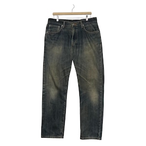 May include: Blue denim jeans with a faded wash and a classic five-pocket design. The jeans are hanging on a wooden hanger against a white background. The denim has a worn appearance.